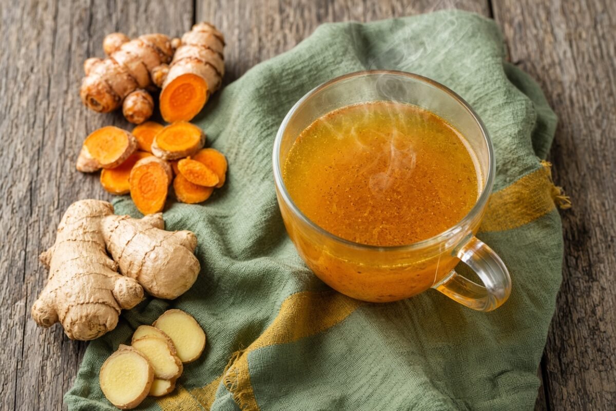 Ginger turmeric tea benefits in a glass mug with fresh roots